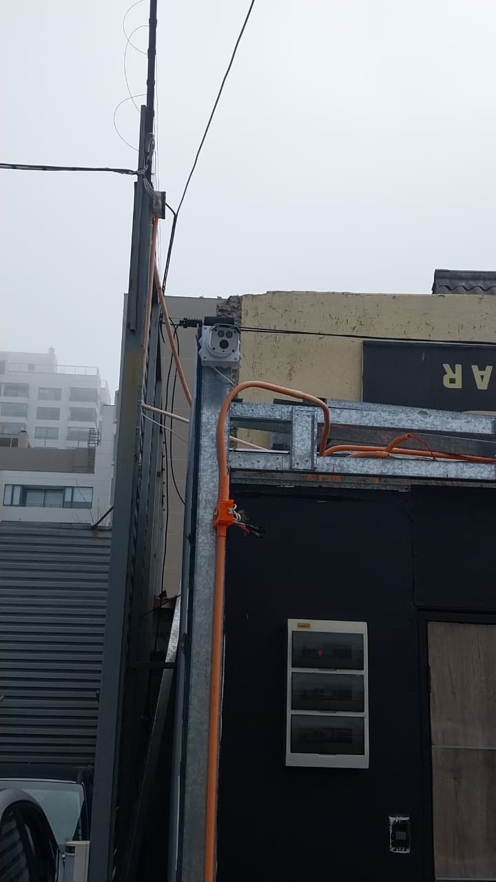 Cámara y canalización naranja en la fachada de un local comercial