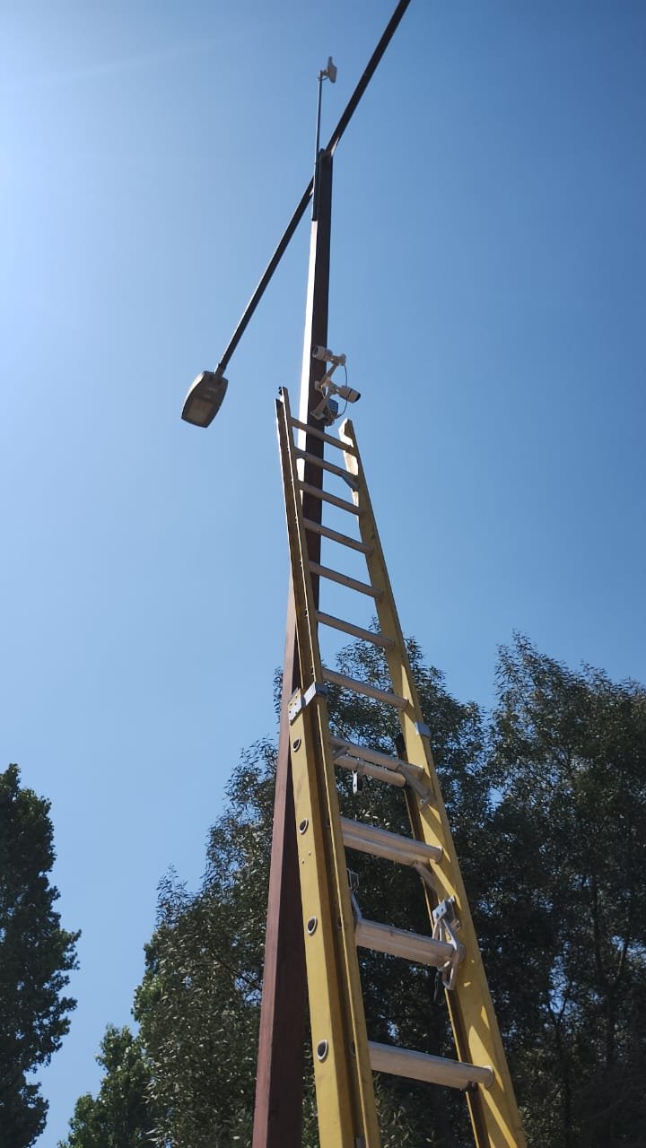 Escalera de fibra apoyada en un poste durante el montaje de cámaras